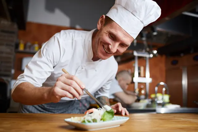 Un chef dresse une assiette à la main
